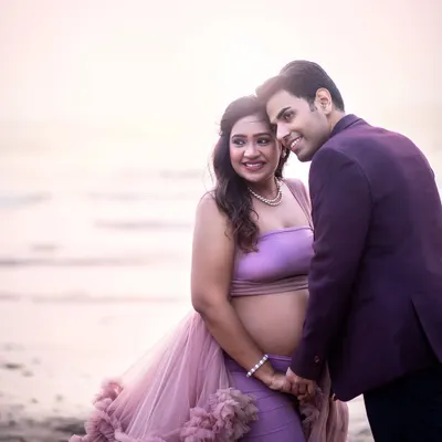 A tender moment on the beach as the sun sets. The soft, blush-toned light creates a romantic and dreamy atmosphere.