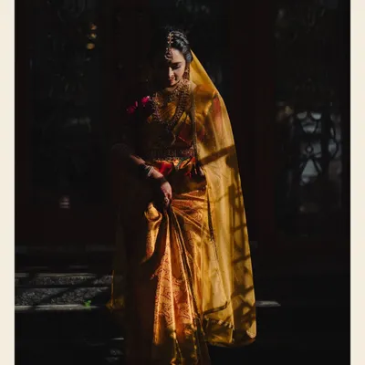 A breathtaking bridal portrait using dramatic lighting to create a powerful and artistic image. The bride, draped in a golden saree, looks like a timeless painting.