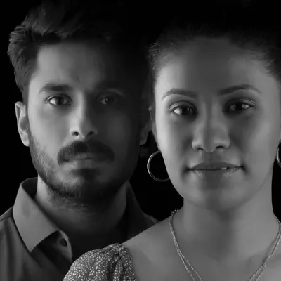 A powerful and direct black and white couple portrait. The dramatic lighting and serious expressions create a moody, high-fashion feel, perfect for couples wanting a creative pre-wedding shoot.