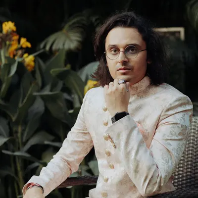 A moment of calm for the groom before the festivities begin. This portrait captures his relaxed yet regal presence, showcasing his elegant wedding attire.