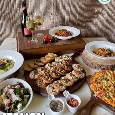 An elegant Italian spread perfect for a celebration. This image features a large bruschetta platter, artisanal pizza, fresh salads, and pasta, paired with sparkling wine for a complete dining experience.