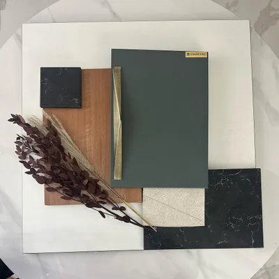 The design process starts with a mood board to capture the right feeling. Here, I've combined samples of wood, marble, and fabric with a subtle sage green and a touch of rustic gold to define the material palette for a project.