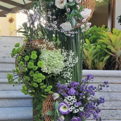 A modern, sculptural floral installation. This piece uses a vertical structure to showcase a variety of flowers and textures, from soft hydrangeas to bold green chrysanthemums, creating a living work of art.