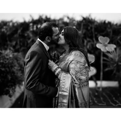 A classic black and white kiss from a post-wedding shoot. The focus is entirely on the couple's intimate moment, creating a powerful and timeless romantic photograph.