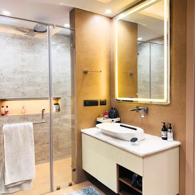 This modern bathroom features a clean, neutral palette with a floating vanity and a large, backlit mirror. The walk-in shower with a glass partition creates a sense of spaciousness and luxury.