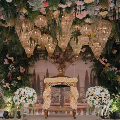 An ethereal Anand Karaj setup featuring a canopy of cascading florals and dozens of crystal chandeliers. The backdrop is a custom-painted mural of a serene landscape, creating a truly magical and otherworldly space for the ceremony.