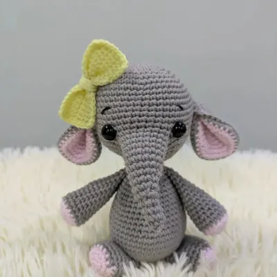 A very cute grey elephant with big ears, pink accents, and a sweet yellow bow on her head.