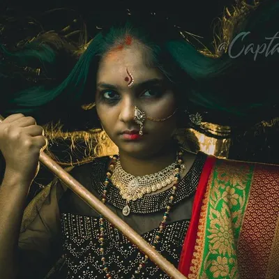 A key image from a conceptual series, this portrait uses a fierce expression and symbolic props to convey strength. The dark, moody lighting and flowing hair create a dramatic, high-impact visual narrative.