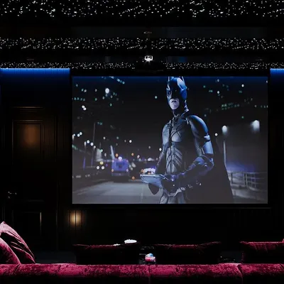Transform your movie nights with a custom-designed home theater. This space features a large screen, a plush red lounge sofa for ultimate comfort, and a star-like fiber optic ceiling to set the perfect cinematic ambiance.
