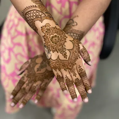 A classic Arabic mehandi design, featuring a bold floral mandala on the back of the hand with patterns extending to the fingers and arm.
