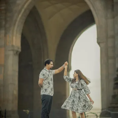 A beautiful, dynamic shot of a couple dancing under the arches of the Gateway of India. This captures the romance and energy of a Mumbai love story.