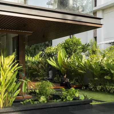 A serene seating nook at Villa re:FORM, nestled within a lush garden and sheltered by the overhead balcony, exemplifying our tropical modern style.