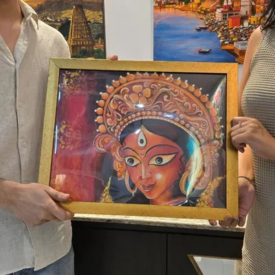 A collector holds a newly purchased, beautifully framed painting of the goddess Durga by artist Simran, a piece from our "Vernissage" exhibition.