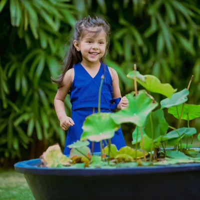 A candid moment of pure joy. This little girl's happy smile as she plays near a lotus pond in a garden is what outdoor photography is all about.
