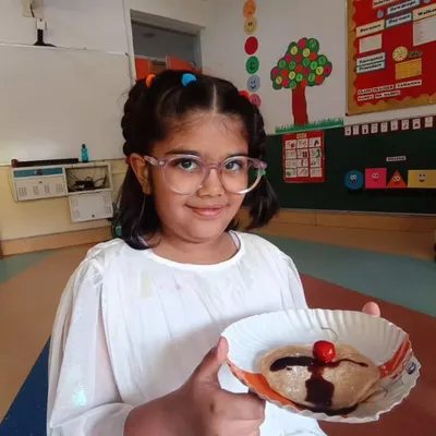 Our culinary arts program is a camp favorite, where children learn basic cooking skills and kitchen safety. This young chef proudly presents her chocolate-drizzled pancake, a delicious result of a hands-on session that combines creativity with practical life skills.