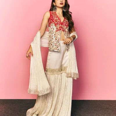A full length shot of Ahsaas Channa styled for a Myntra festive campaign. This modern ethnic look features a sharara with a beautifully embroidered red jacket, perfect for festive occasions.