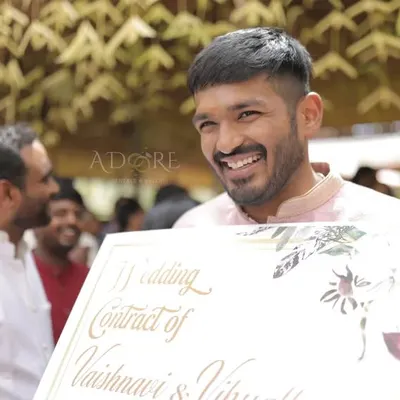 The groom happily signing a fun wedding contract presented by the bride's family. These playful rituals are a great way to kick off the celebrations.