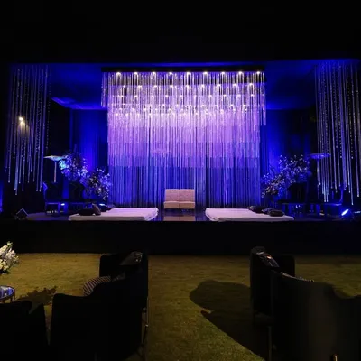 I designed this sangeet stage with a waterfall of shimmering crystal strings under deep blue light, creating a backdrop that was both regal and romantic for an evening of performances.