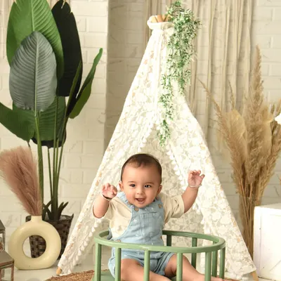 A joyful, hands-in-the-air moment during a boho-themed sitter session. The natural elements like the teepee and plants create a calming and beautiful environment.