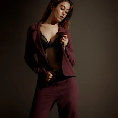 A moody, low-key portrait focusing on form and texture. The lighting is shaped to highlight the model's pose and the fabric of the suit, creating a sense of quiet confidence.