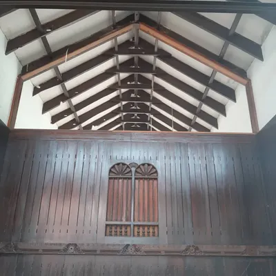 The interior of a traditional home during restoration, showcasing the original exposed wooden rafters and intricately carved wall panels. My goal is to protect and highlight these irreplaceable heritage details.