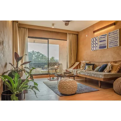 The living room of a villa at Svamitva Terravana, featuring lime-plastered walls and natural Kota stone flooring. The large sliding doors open to the outdoors, blurring the boundary between the interior and the landscape.