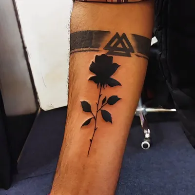 We covered an old tattoo with this bold black rose and armband design. The negative space technique makes the rose pop, completely concealing what was underneath.