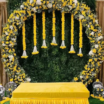 A popular choice for modern pre-wedding functions, this circular arch is completely covered in yellow and white flowers. Paired with a green foliage wall, it provides a vibrant and stylish setting for your Haldi.