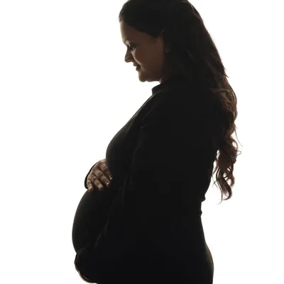 A classic black and white silhouette portrait. This timeless style focuses on the beautiful outline of the baby bump, creating a simple yet powerful and artistic image.