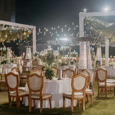A magical dinner setting under the stars. We used hanging greenery, Edison bulbs, and elegant white table settings to create a 'Luxe Garden' reception that felt both grand and romantic.