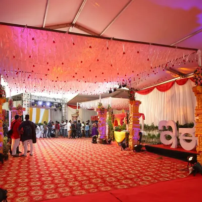 A wide view of the main event hall for the Zee Kannada awards, showing the large stage, patterned red carpet, and elegant ceiling decor with hanging white tassels and soft lighting.