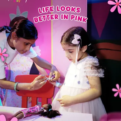 Life looks better in pink! A little girl gets a hair accessory put in while playing with her Barbie doll. Our Barbie Style Studio is all about pink-powered fun and creativity.
