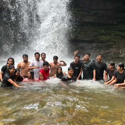 A group of trekkers enjoying a refreshing dip in a waterfall pool during the Nethravathi trek.