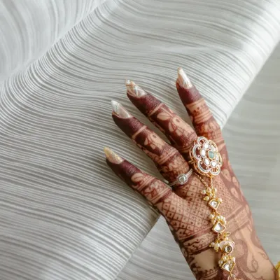 A close-up shot of the bride's hand, showcasing the intricate mehendi design and a beautiful traditional hathphool.