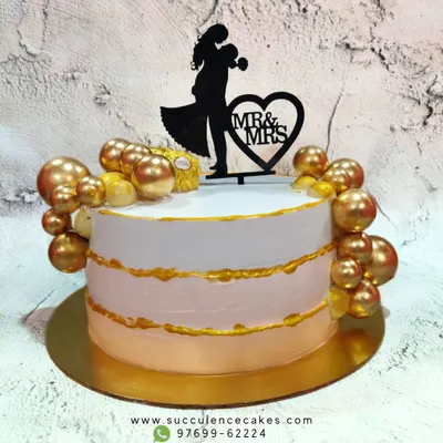 A beautiful and elegant cake to celebrate a new chapter as Mr. & Mrs. The design features a soft pink and white ombre effect with gold accents and is topped with a silhouette of the couple, perfect for an engagement or anniversary.