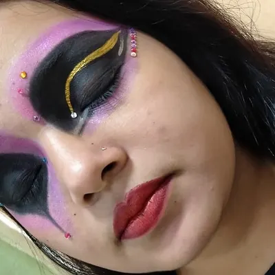 We encourage our students to push their creative boundaries. This is an example of fantasy makeup practice, focusing on advanced techniques like sharp graphic eyeliner, color blending with purple and black, and precise rhinestone application.