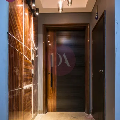 The entrance to this home makes a statement with a mix of rich textures. I used a glossy, wood-grain panel with inlaid details next to a modern, ribbed black door. The pendant lights add a final touch of drama.