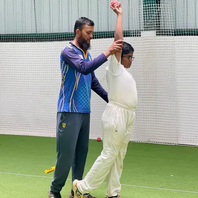 Our coaches provide hands-on guidance to perfect every aspect of the game. Here, a coach corrects a young bowler's arm position to ensure a clean, effective, and injury-free action.