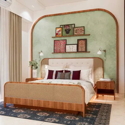 Colorful ethnic vibes in this stunning master bedroom. The design features a beautiful cane and wood bed frame, a sage green textured accent wall with an arch detail, and a curated collection of traditional Indian art.