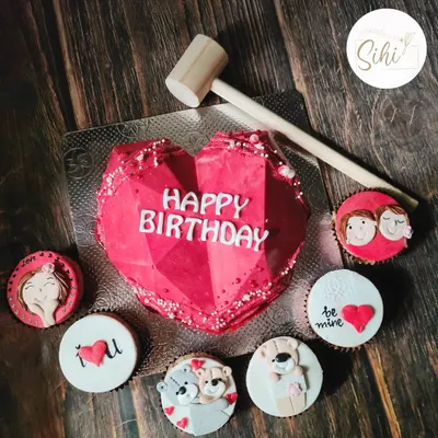 A smashable heart piñata cake is such a fun way to celebrate a birthday. This one comes with a hammer and is paired with adorable, love-themed cupcakes.