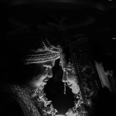 A powerful black and white shot capturing the bride and groom in a moment of intense connection. The dramatic lighting focuses on their faces, creating a timeless and deeply emotional wedding portrait.