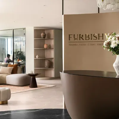 The entrance to our Hyderabad studio, featuring our custom-designed curved reception desk and prominent branding. This view shows the transition from the black marble flooring to the living area, setting a tone of modern, sculptural elegance right from the first step.
