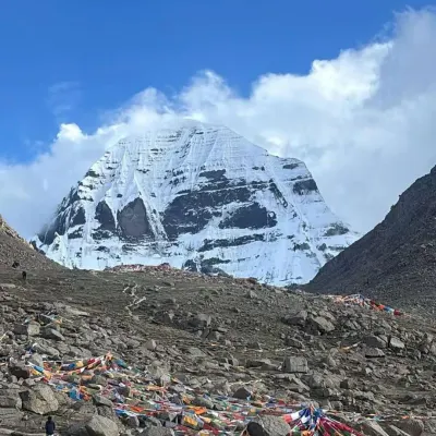A wide view of Mount Kailash, showing the rugged terrain and prayer flags that mark the path. This trek is as much an adventure as it is a pilgrimage.