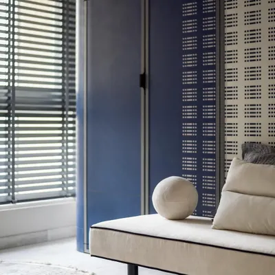 This children's room was designed with space-saving solutions like a Murphy bed to maximize play area. The blue and white color scheme is fresh and modern, with custom perforated wardrobe doors adding a unique touch.