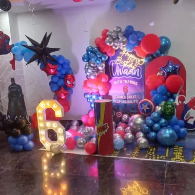An action-packed Avengers theme for a 6th birthday. This setup includes a large backdrop, marquee number, character cutouts like Batman and Spider-Man, and a balloon arrangement in superhero colors.