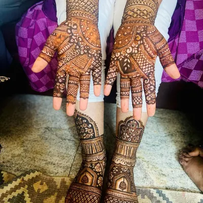 A full view of a stunning bridal mehendi set after the henna paste has dried. The designs on the hands and feet are created to match, featuring traditional Indian motifs for a cohesive and beautiful bridal look.
