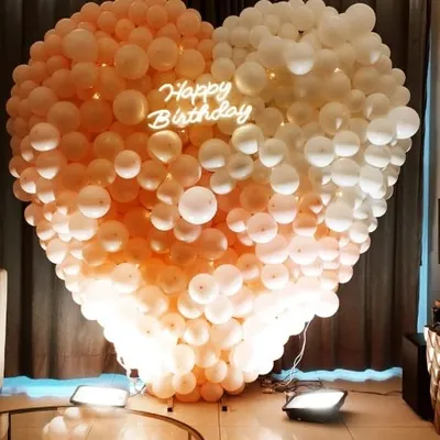 This is a large, heart-shaped balloon wall I created for a birthday party. The design uses an ombre color effect and features a custom "Happy Birthday" neon sign in the center.