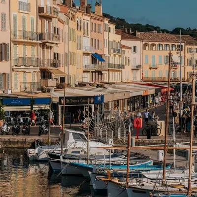 The bustling harbor of St. Tropez, with its classic waterfront buildings and docked boats. This image captures the vibrant atmosphere of the French Riviera in summer.