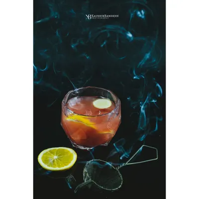 A smoky citrus cocktail against a dark, moody background. I use techniques like smoke to add drama and atmosphere, creating an alluring image for a bar's specialty drink menu.