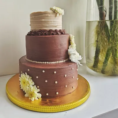 This three-tiered chocolate wedding cake was designed to be both rustic and elegant. Each tier has a different texture, and it's adorned with fresh white flowers for a touch of natural beauty.